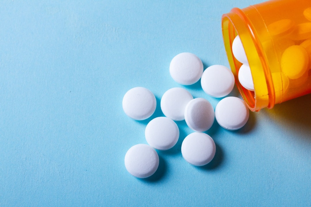 A bottle of prescription meds spilled onto a blue backgraound.