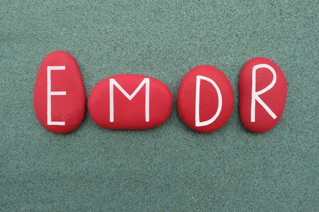 Four smooth stones painted red with the letters E, M, D, R painted on them.